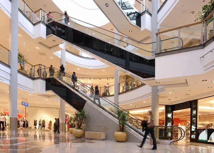 Shoppers on escalators inside a large multi level shopping centre