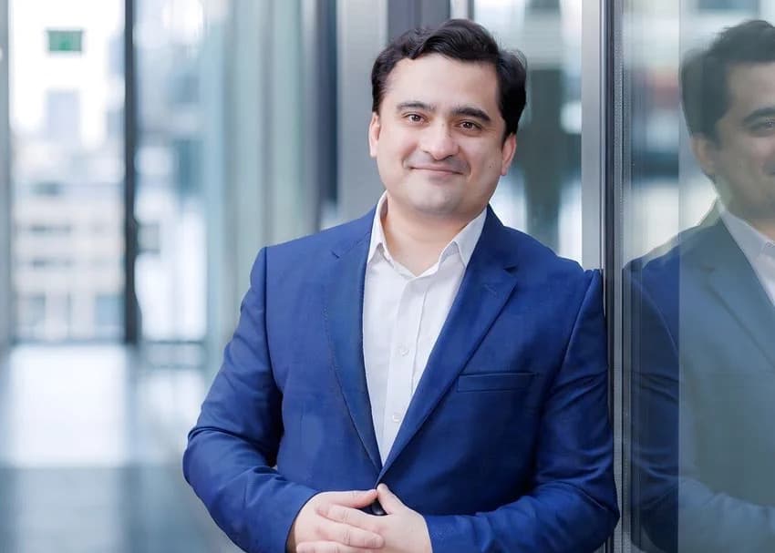 A portrait of a business executive standing by a glass wall