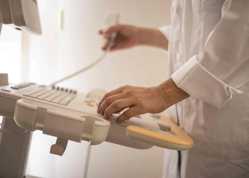 A clinician operates an ultrasound machine console