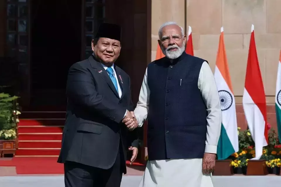 Indonesian President Prabowo Subianto shakes hands with Indian Prime Minister Narendra Modi in front of the Indonesian and Indian flags