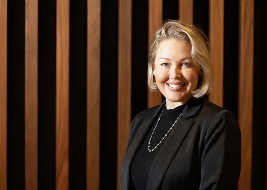 A portrait of a business executive standing in front of a wood paneled wall