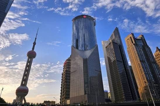 The Lujiazui financial district skyline in Shanghai, with the Oriental Pearl Tower against a blue sky