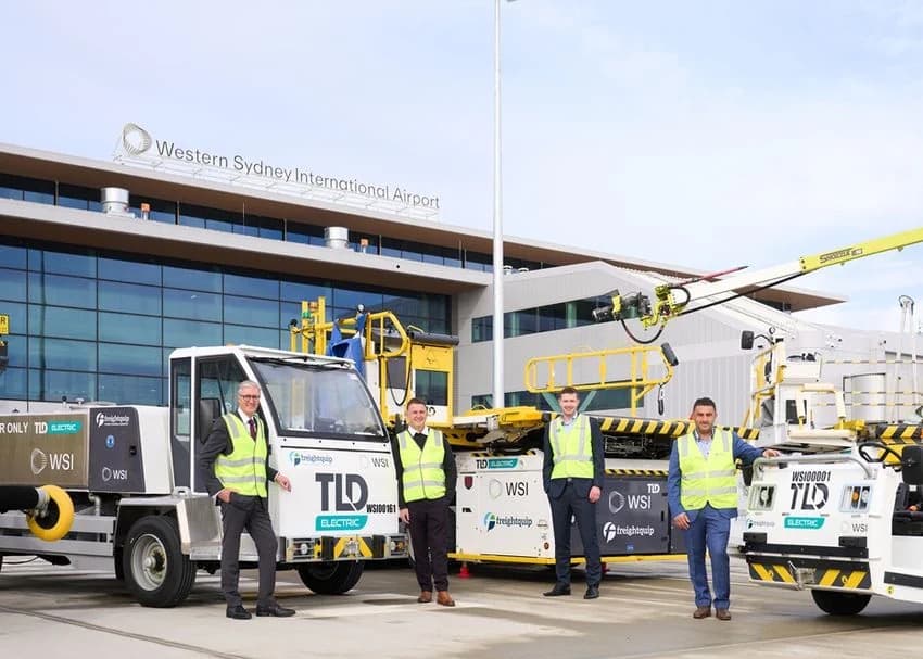 Four men in high visibility vests standing in front of electric ground support vehicles at Western Sydney International Airport