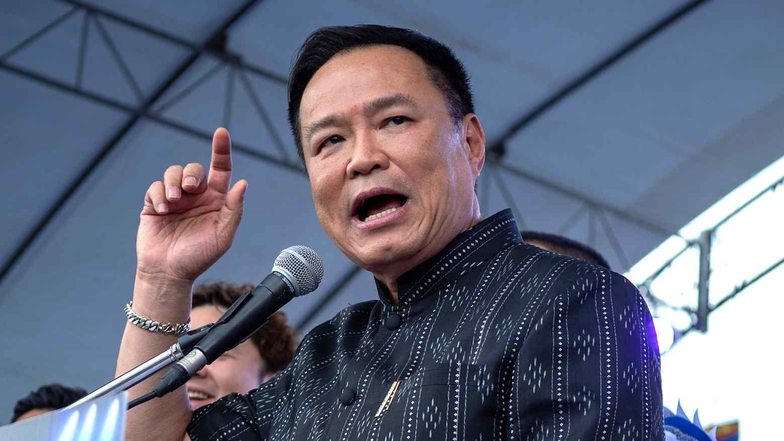 Thai Prime Minister Anutin Charnvirakul speaking at a microphone with a raised hand