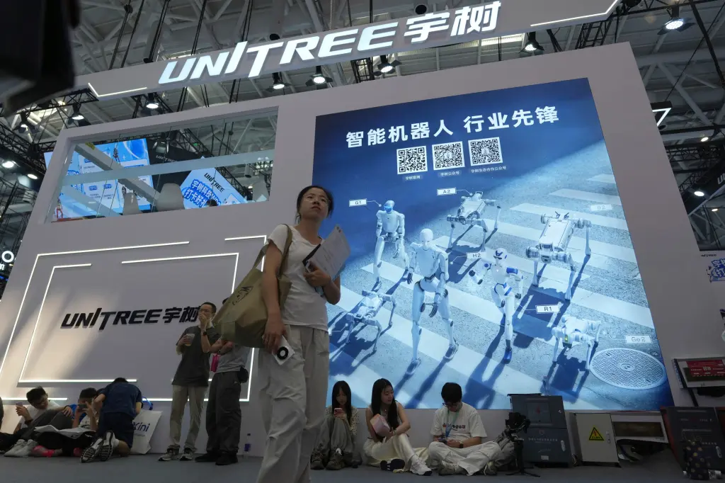 A visitor walks past the Unitree robotics booth displaying humanoid robots at a trade show