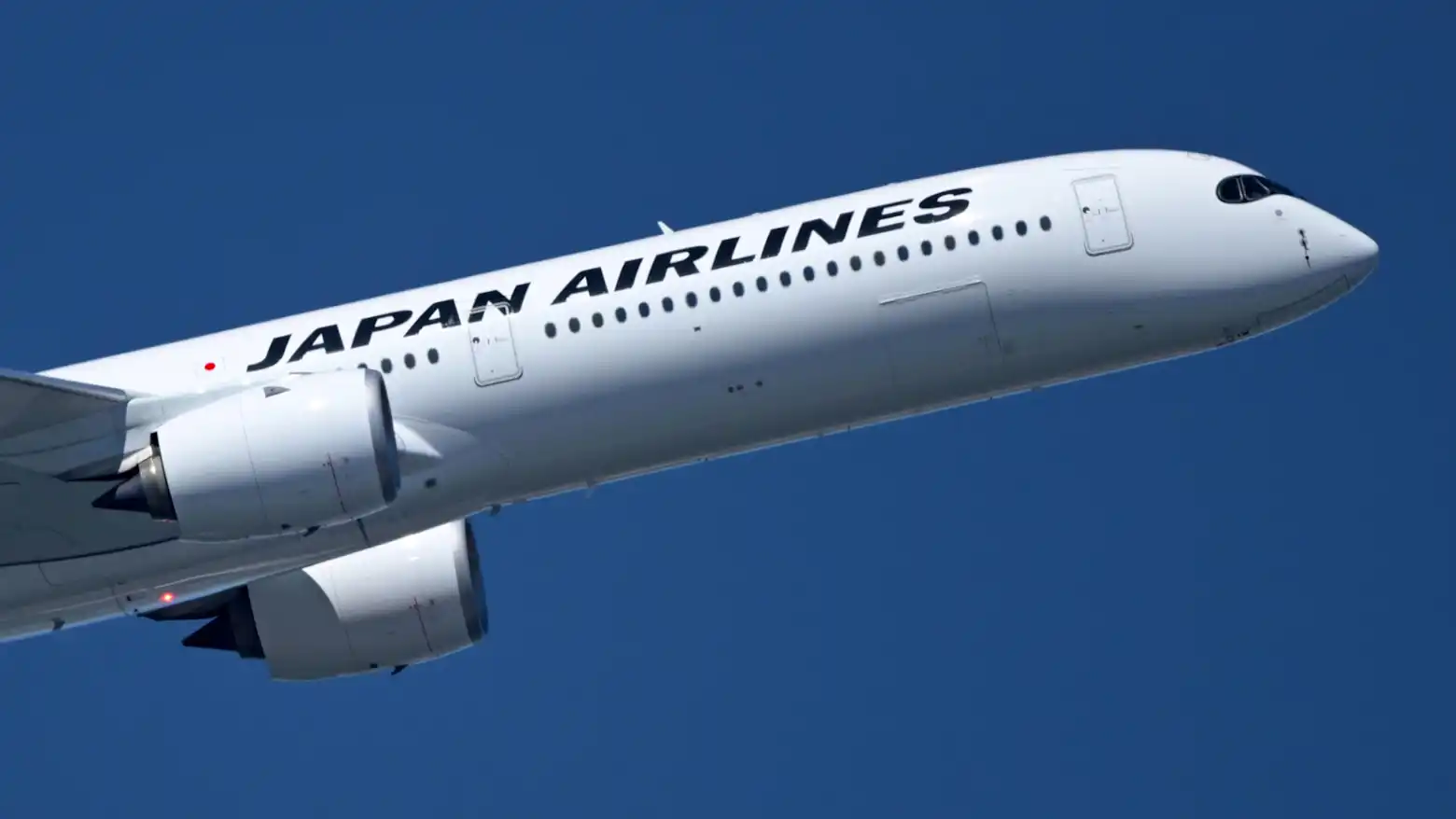A Japan Airlines aircraft climbing against a clear blue sky