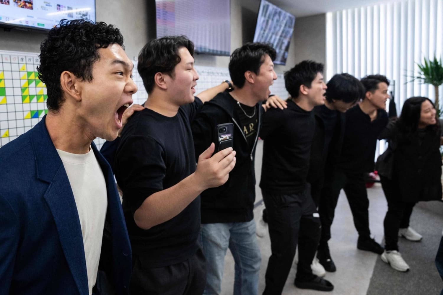 Young employees at Tokyo firm Global Partners chant work targets shoulder to shoulder during a morning rally