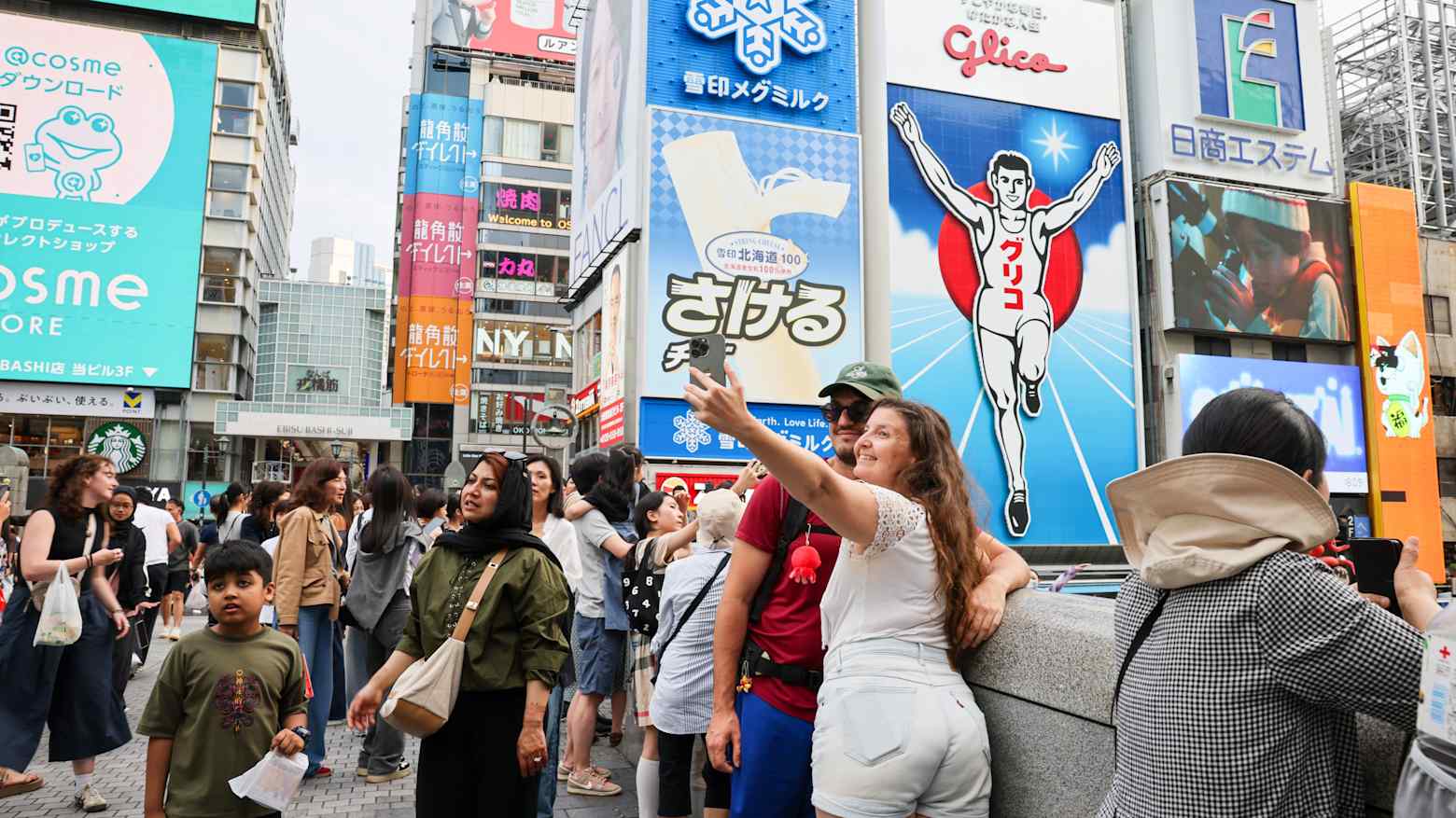 Crowds of tourists and shoppers gather beneath the neon billboards of Osaka's Dotonbori district