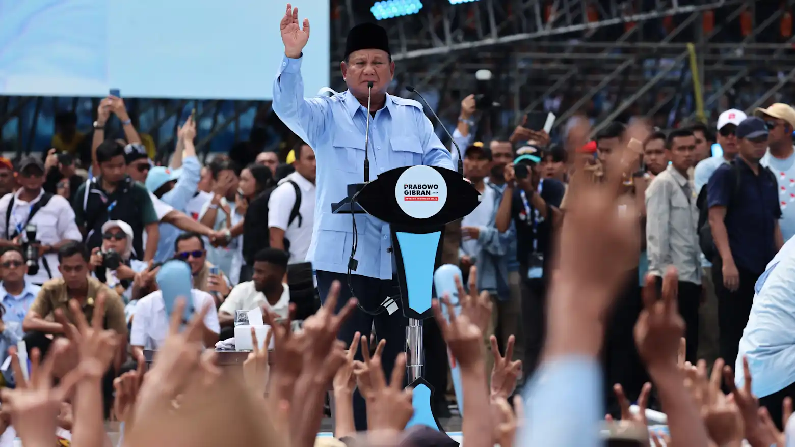Indonesian President Prabowo Subianto waving to a crowd at a rally podium