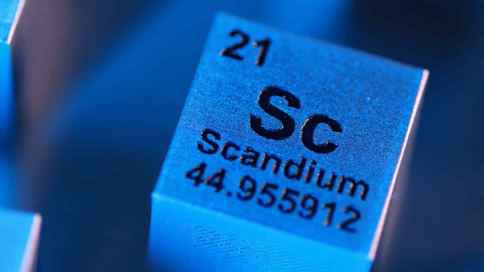 A blue metal cube labeled with the element symbol Sc for scandium, atomic number 21