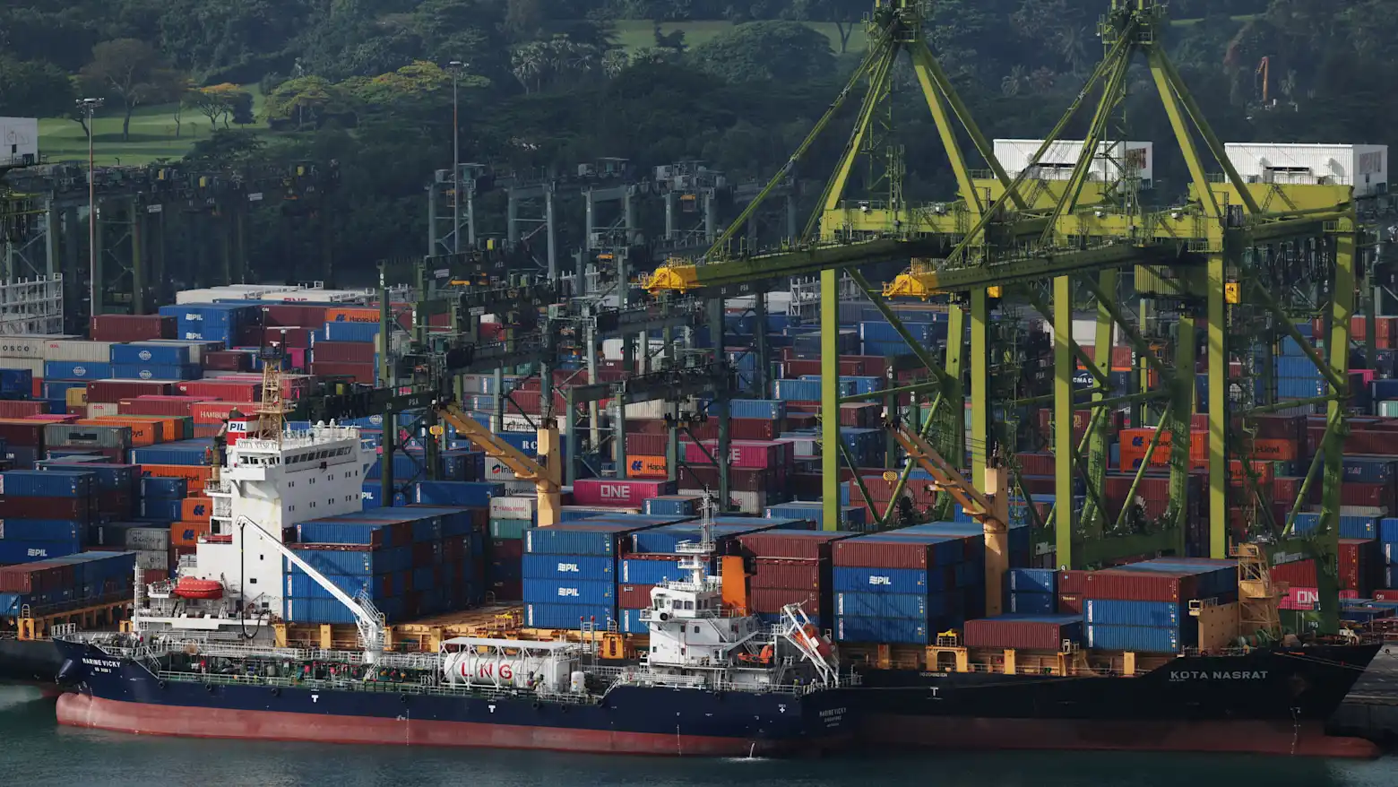 Aerial view of container ships loading and unloading at a busy Singapore port terminal with gantry cranes