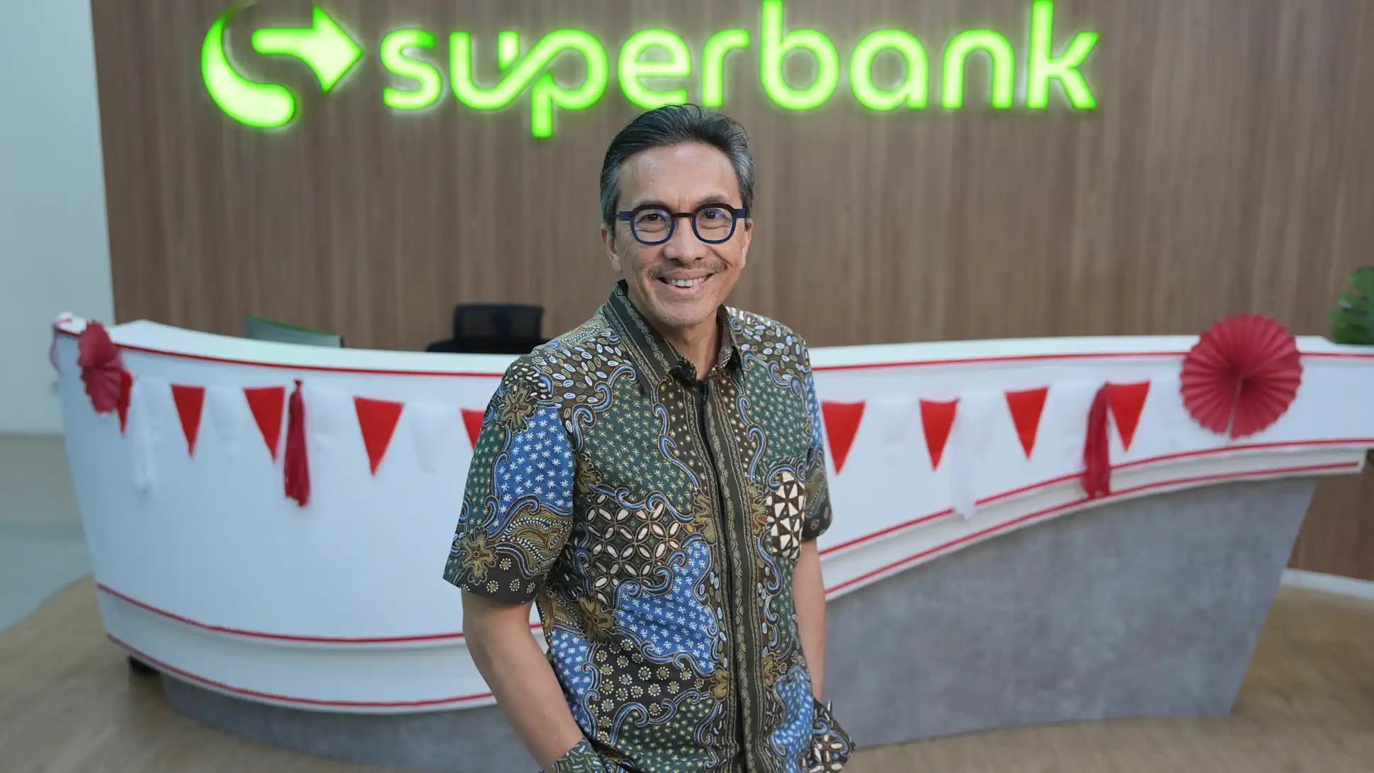 Superbank CEO Tigor Siahaan standing in front of the Superbank logo