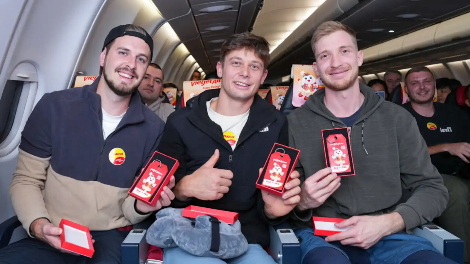 Passengers aboard a Vietjet aircraft smiling and holding souvenir gift tags during the airline's inaugural flight